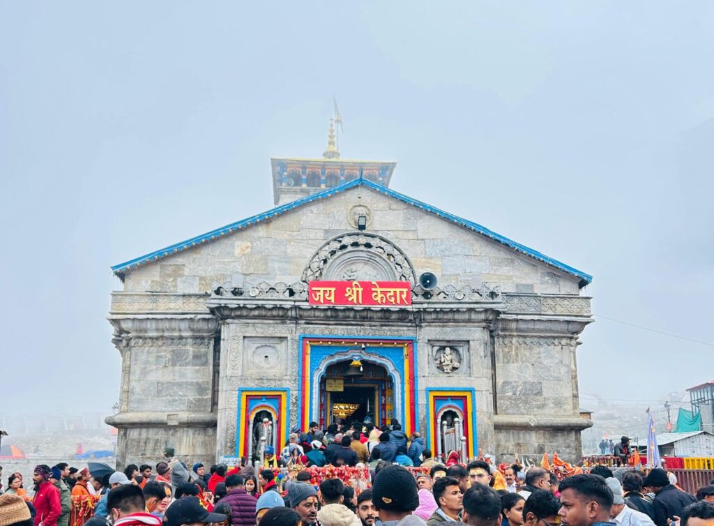 A large crowd gathers at the historic Kedarnath Temple in India amidst misty weather.